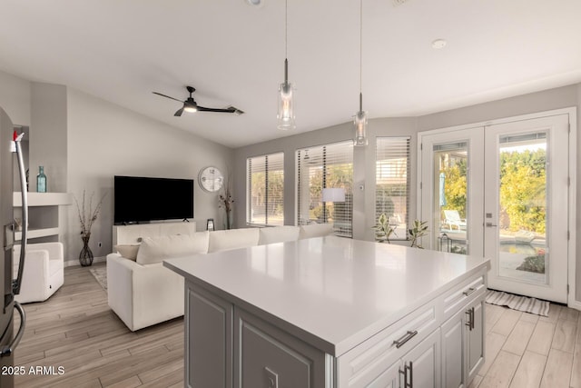 kitchen with decorative light fixtures, a wealth of natural light, white cabinets, and a kitchen island