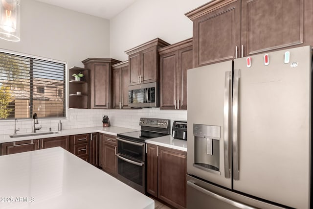 kitchen with appliances with stainless steel finishes, hanging light fixtures, sink, dark brown cabinetry, and backsplash