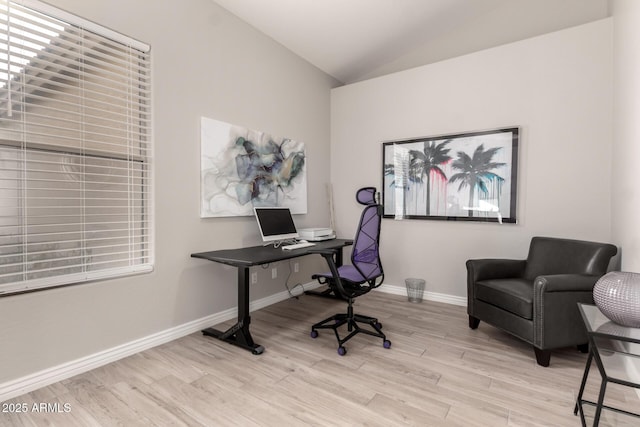 home office with light wood-type flooring and vaulted ceiling