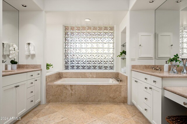 bathroom featuring tile floors, a relaxing tiled bath, and vanity with extensive cabinet space