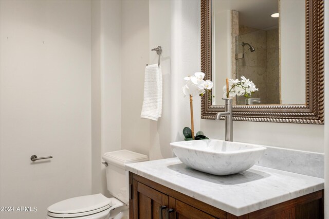 bathroom with a tile shower, toilet, and vanity with extensive cabinet space