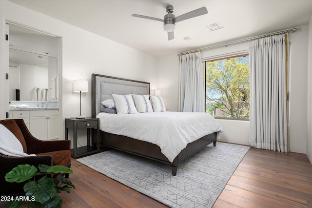 bedroom featuring sink, hardwood / wood-style flooring, ceiling fan, and ensuite bath