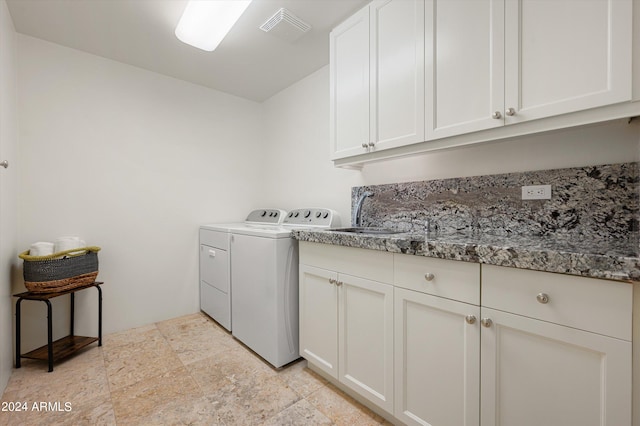 laundry room with washing machine and clothes dryer, cabinets, and light tile floors