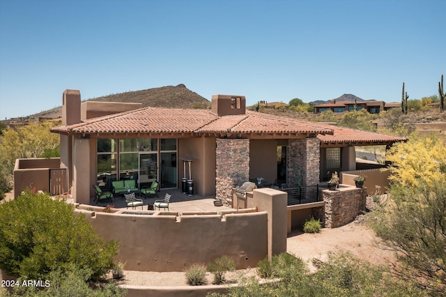 rear view of house with a patio, stucco siding, outdoor lounge area, stone siding, and a tiled roof