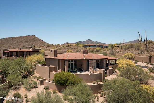 back of house with a patio area, a mountain view, and stucco siding