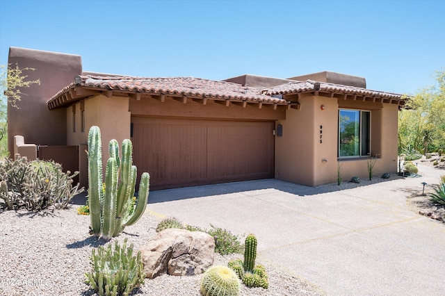 view of front of home featuring concrete driveway, an attached garage, a tiled roof, and stucco siding