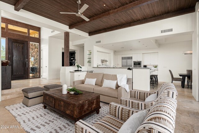 tiled living room featuring ceiling fan, a high ceiling, beam ceiling, and wood ceiling