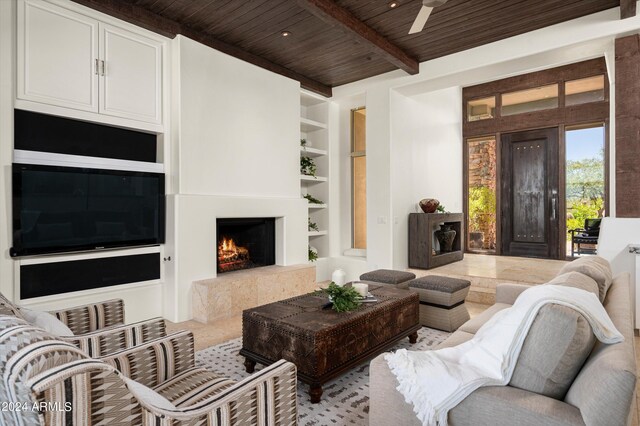 living room featuring built in features, ceiling fan, beamed ceiling, and wooden ceiling