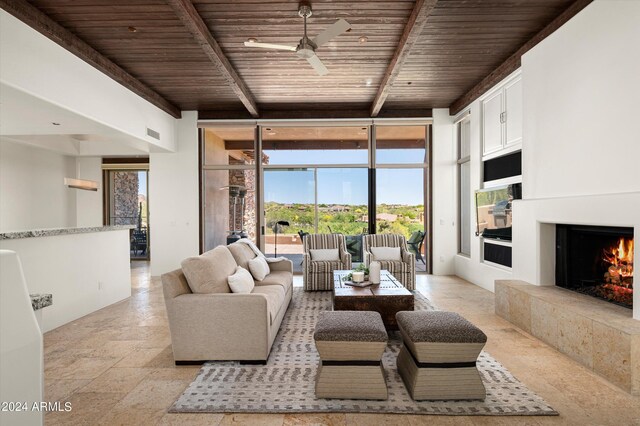 living room with ceiling fan, a tile fireplace, light tile flooring, and wooden ceiling