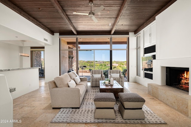 living area featuring a warm lit fireplace, wooden ceiling, a wall of windows, stone tile floors, and beamed ceiling