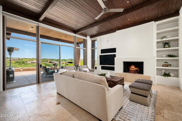 living room featuring built in features, beamed ceiling, plenty of natural light, and wood ceiling