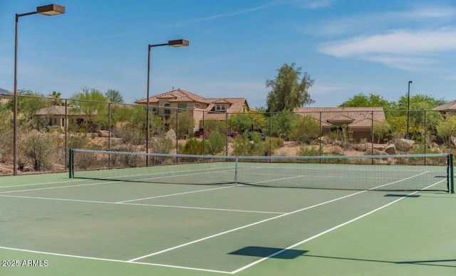 view of tennis court featuring community basketball court and fence