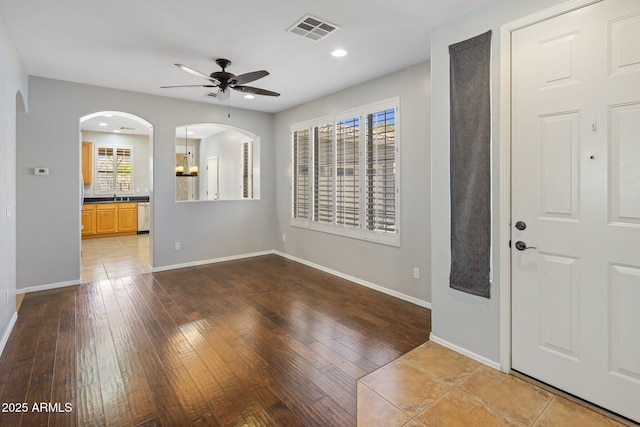 entryway featuring wood-type flooring, a ceiling fan, arched walkways, and visible vents
