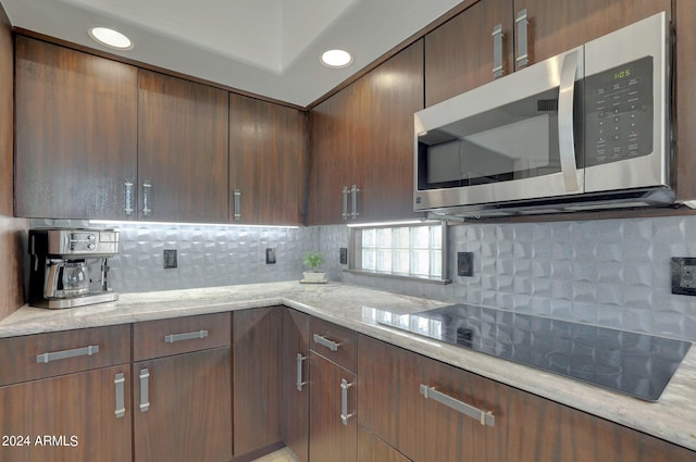 kitchen featuring tasteful backsplash, black electric cooktop, and light stone countertops