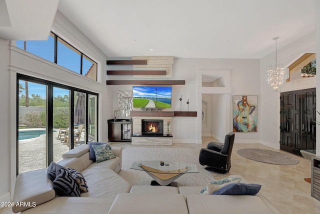 living room with a stone fireplace, plenty of natural light, french doors, and a notable chandelier