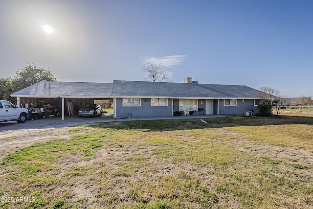 single story home with central AC unit, an attached carport, a chimney, and a front yard