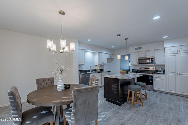 dining room with sink, an inviting chandelier, and light wood-type flooring