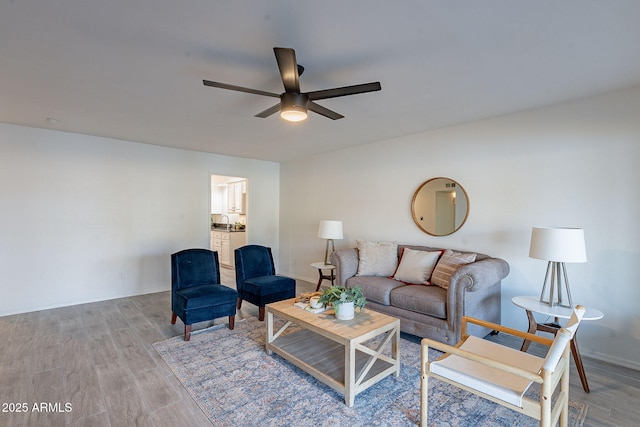 living room featuring ceiling fan, sink, and light wood-type flooring