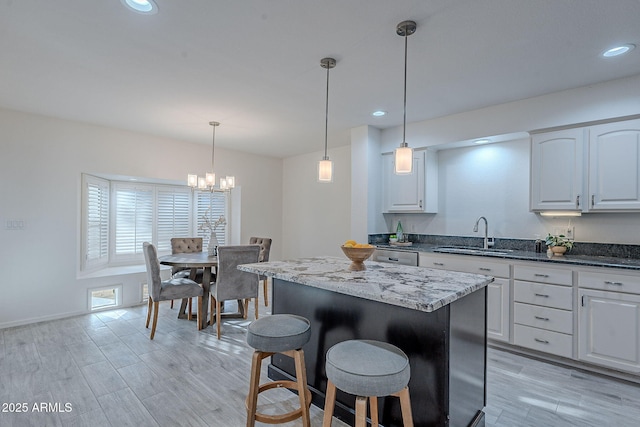 kitchen featuring white cabinetry, a center island, sink, and dark stone countertops