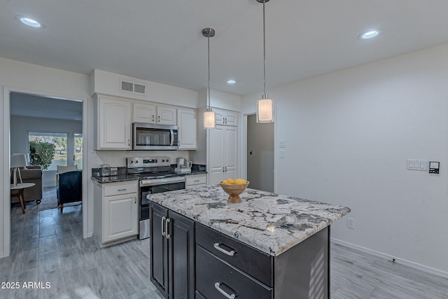 kitchen with pendant lighting, stainless steel appliances, light hardwood / wood-style flooring, and white cabinets