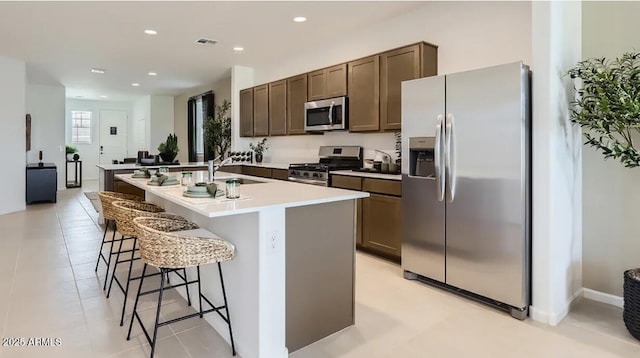 9621 W Monterey Way, Phoenix, AZ 85037 - kitchen with appliances with stainless steel finishes, a kitchen island with sink, a kitchen breakfast bar, dark brown cabinetry, and recessed lighting