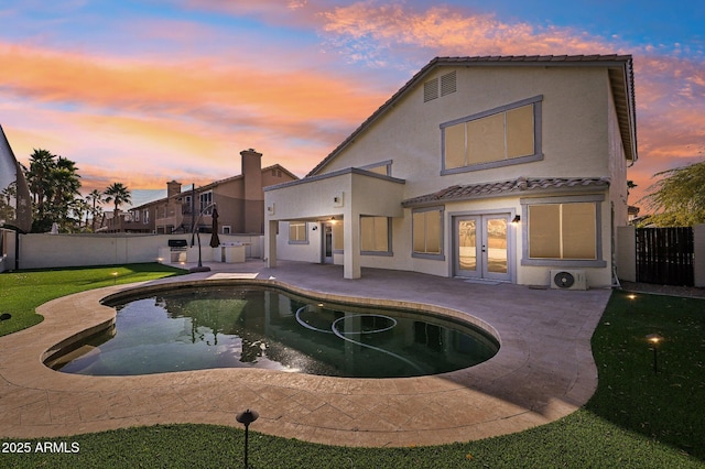 pool at dusk featuring a lawn, french doors, and a patio