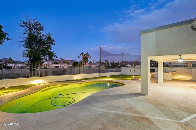 pool at dusk featuring a patio and a mountain view