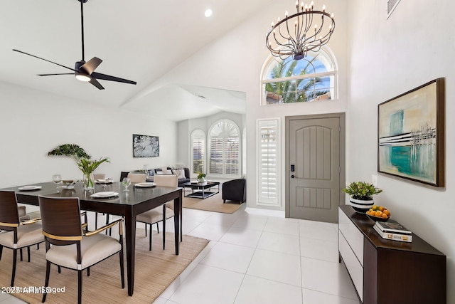 tiled foyer entrance with high vaulted ceiling and ceiling fan with notable chandelier