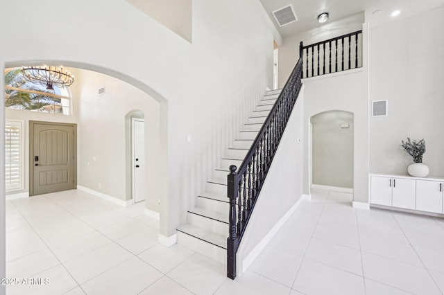 entryway with a high ceiling, a notable chandelier, and light tile patterned floors