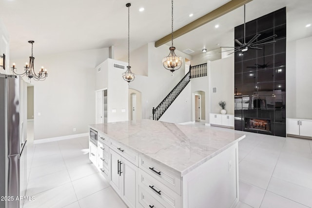 kitchen featuring stainless steel appliances, white cabinets, a center island, ceiling fan with notable chandelier, and beam ceiling