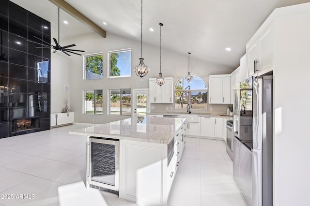 kitchen with decorative light fixtures, white cabinetry, a center island, beverage cooler, and beam ceiling