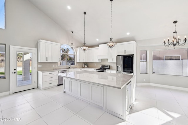 kitchen with stainless steel appliances, white cabinets, a center island, hanging light fixtures, and a chandelier