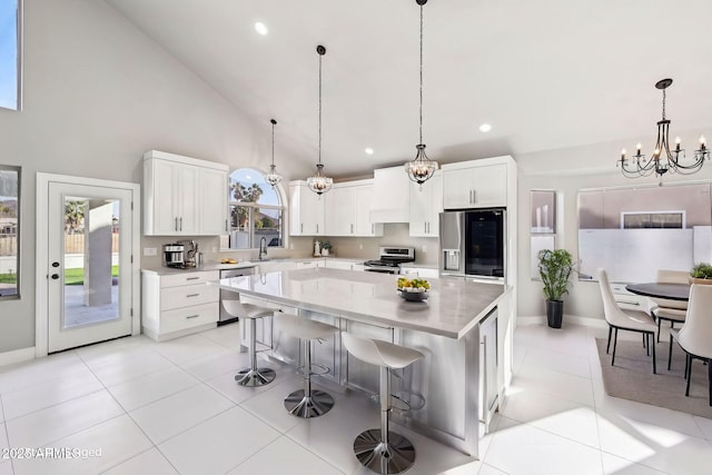 kitchen featuring stainless steel appliances, a center island, an inviting chandelier, white cabinetry, and a kitchen bar