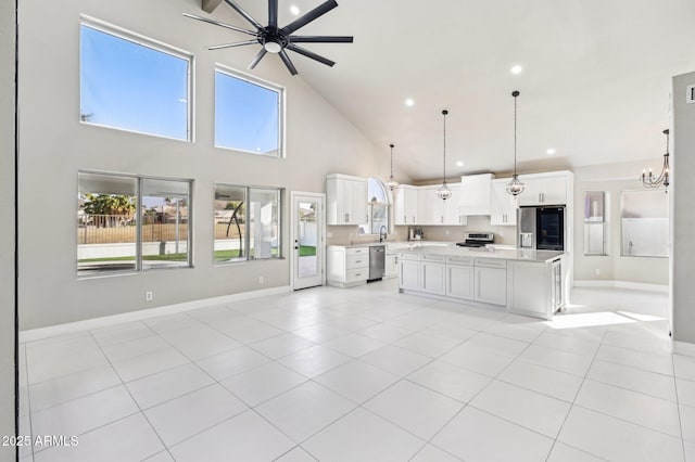 kitchen with pendant lighting, a center island, stainless steel appliances, ceiling fan with notable chandelier, and white cabinets