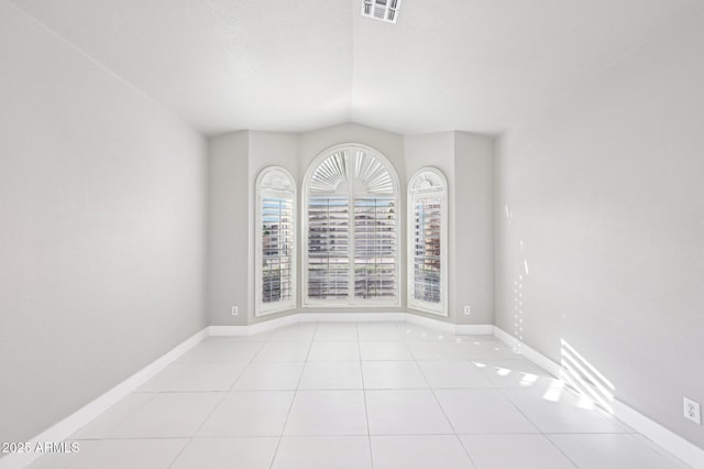 empty room with vaulted ceiling and light tile patterned floors