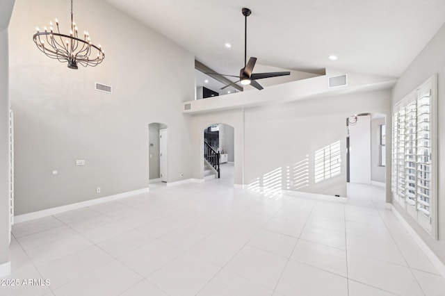 unfurnished living room with a towering ceiling, ceiling fan with notable chandelier, and light tile patterned floors