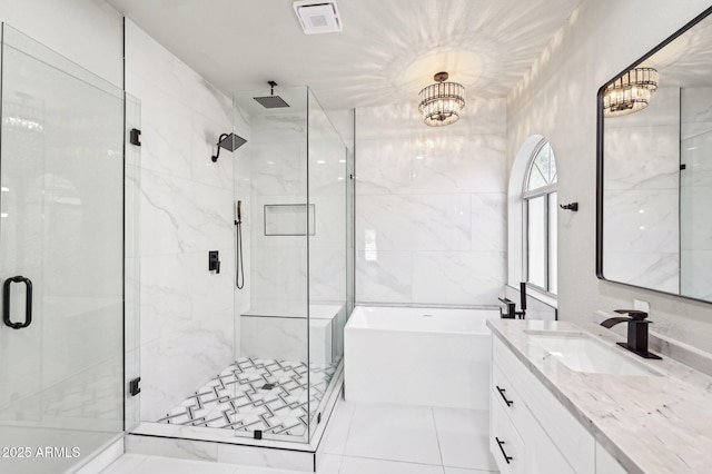 bathroom with tile walls, an inviting chandelier, plus walk in shower, and vanity