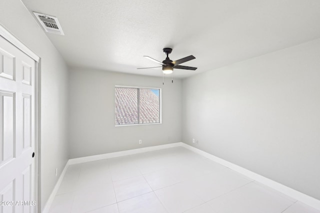 unfurnished room with a textured ceiling, ceiling fan, and light tile patterned floors