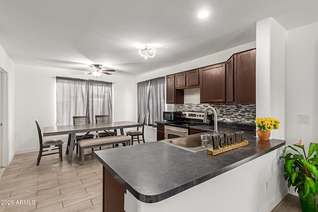 7725 S 47th Ln, Laveen, AZ 85339 - kitchen with stainless steel electric stove, dark countertops, dark brown cabinets, decorative backsplash, and ceiling fan