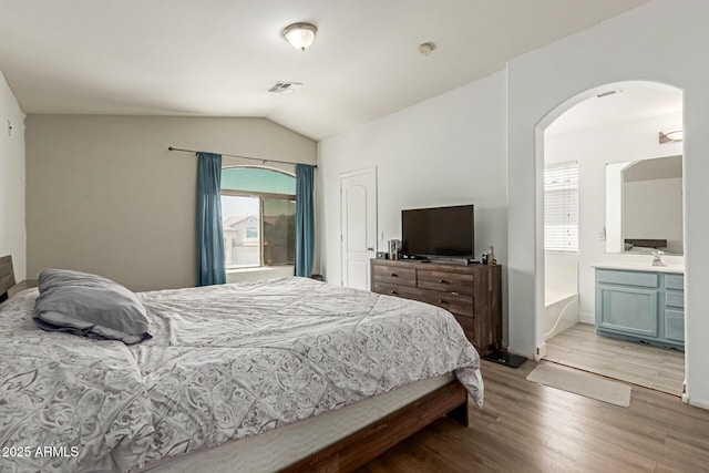 7725 S 47th Ln, Laveen, AZ 85339 - bedroom featuring arched walkways, light wood-style flooring, lofted ceiling, and ensuite bathroom
