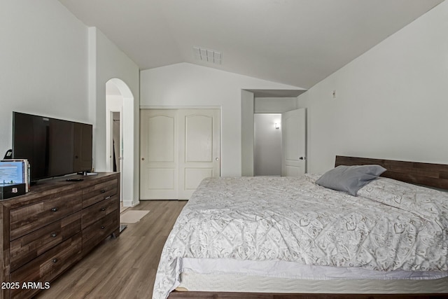 7725 S 47th Ln, Laveen, AZ 85339 - bedroom featuring wood finished floors, vaulted ceiling, arched walkways, and a closet