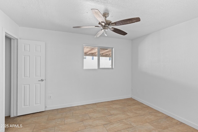 spare room with ceiling fan, a textured ceiling, and baseboards