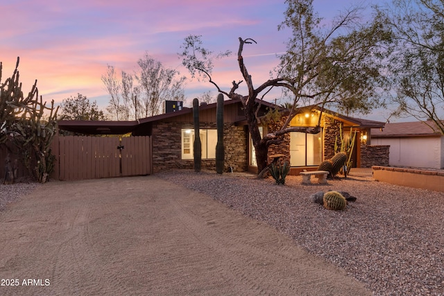 mid-century modern home with stone siding and fence