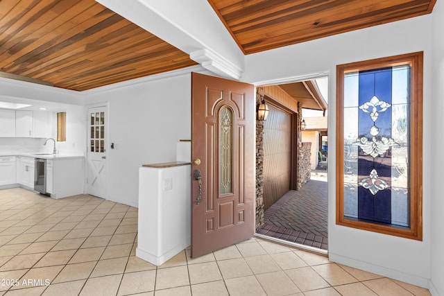 foyer with light tile patterned floors, wooden ceiling, and baseboards