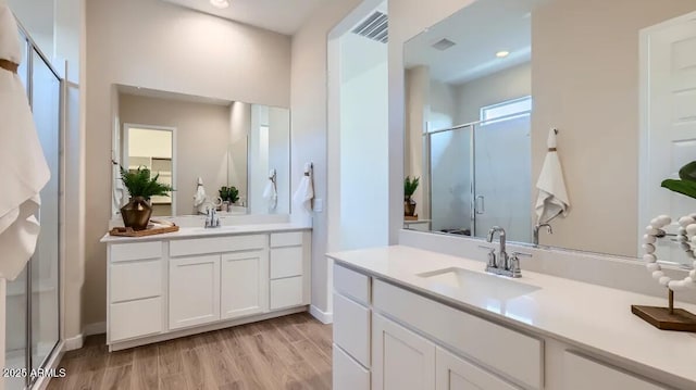 23244 W Tamarisk Ave, Buckeye, AZ 85326 - bathroom with a stall shower, two vanities, wood finished floors, and recessed lighting