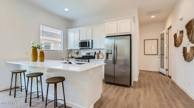 23244 W Tamarisk Ave, Buckeye, AZ 85326 - kitchen featuring appliances with stainless steel finishes, a breakfast bar, light wood-style floors, a peninsula, and light countertops