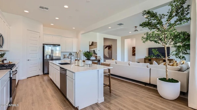 23244 W Tamarisk Ave, Buckeye, AZ 85326 - kitchen with open floor plan, appliances with stainless steel finishes, a kitchen breakfast bar, white cabinets, and light wood-style flooring