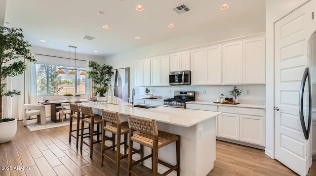 23244 W Tamarisk Ave, Buckeye, AZ 85326 - kitchen with stainless steel appliances, light wood-type flooring, light countertops, a kitchen bar, and white cabinetry