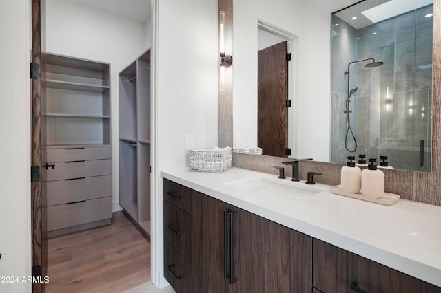 bathroom with a skylight, vanity, a shower with shower door, and hardwood / wood-style floors