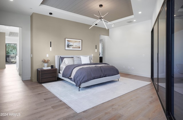 bedroom with light wood-type flooring and a raised ceiling